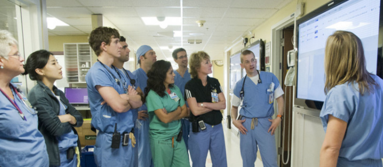 A group of medical students surround a screen during their education.