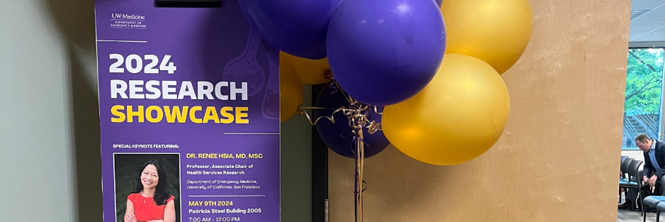 Photo of the research showcase poster sitting outside the meeting room with purple and gold balloons