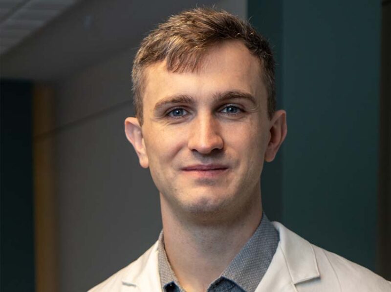 Headshot of Dr. Michael Zylstra in a white coat against a grey and blue wall