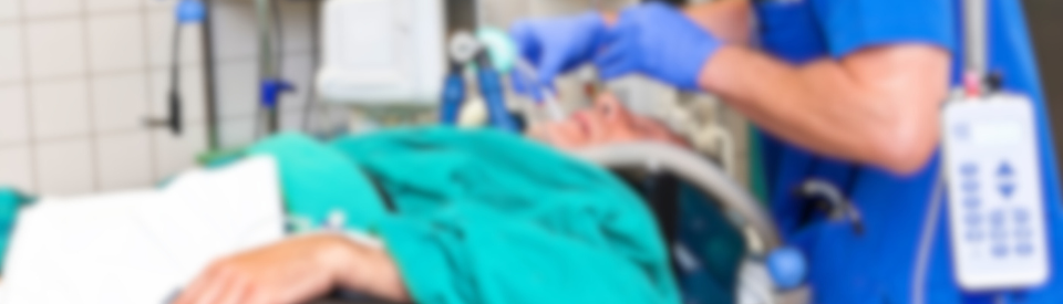 Stock photo of a patient on a breathing tube with a doctor standing over them.