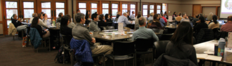 An audience sits and listens to the presenter at the Symposium.