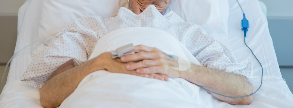 A stock photo of an elderly male patient lying in a hospital bed.