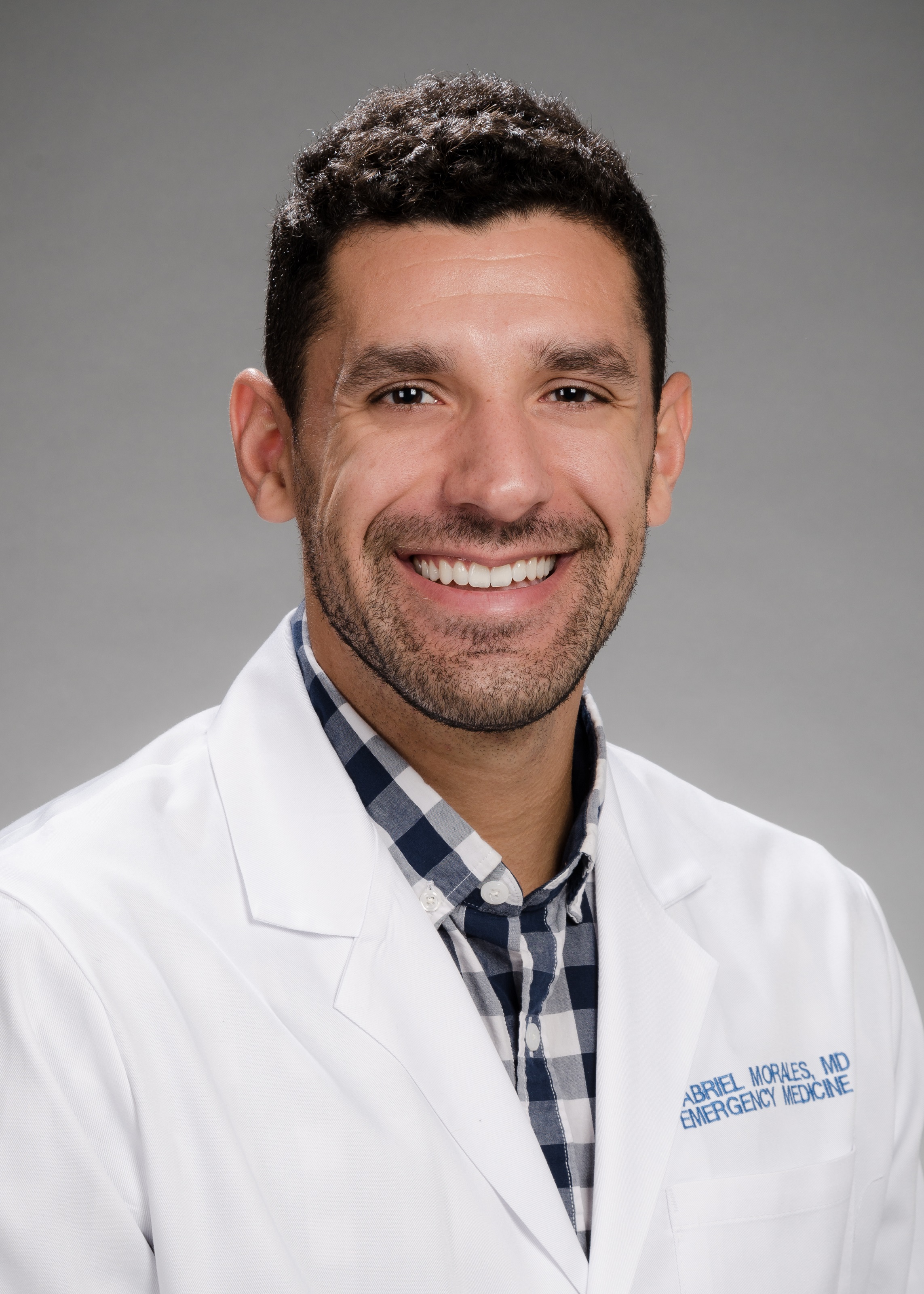 Headshot of Dr. Gabe Morales in his white coat against a gray background 