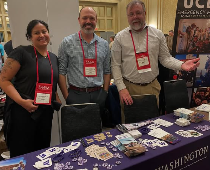 Drs. Sachita Shah, Doug Franzen, and Chris Buresh stand by the UW EM table at the residency fair.