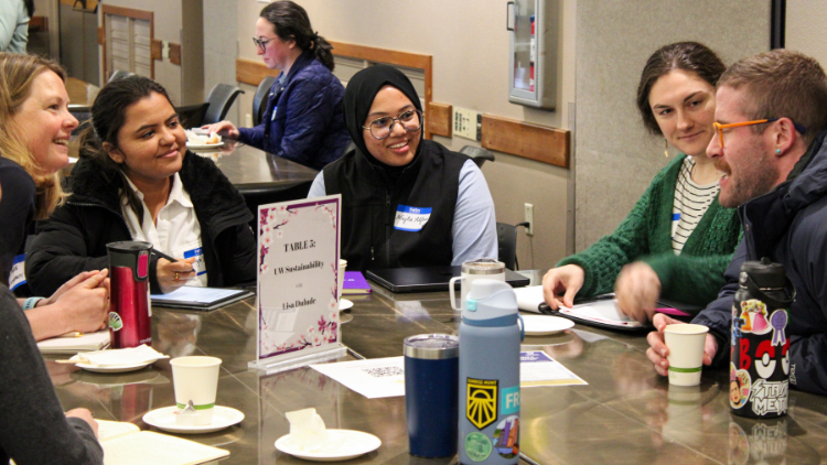 Symposium attendees sitting at a table during break out discussion sessions.