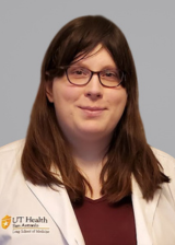 Headshot of Jessica Gray wearing a white coat against a blue-gray background