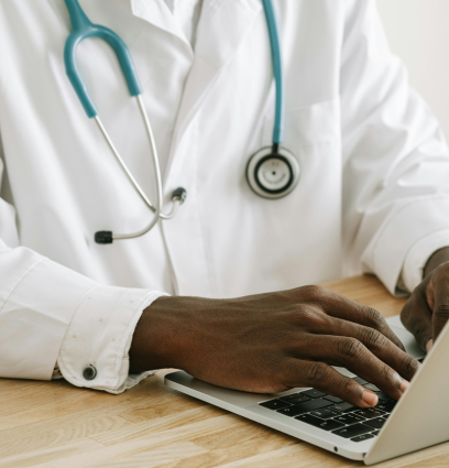 A close up view of a doctor's hands typing on a laptop