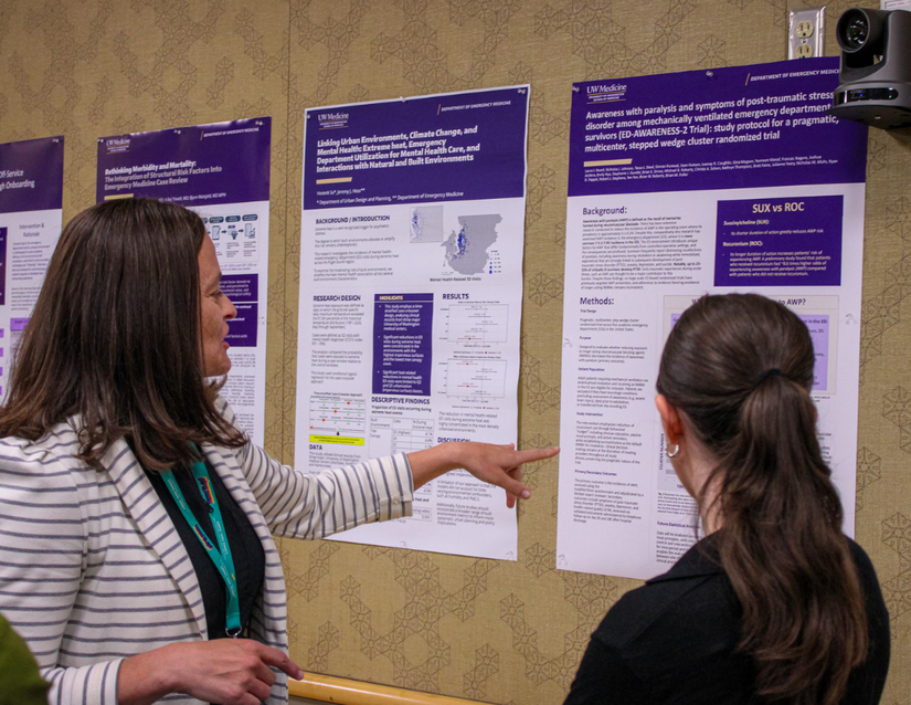 Dr. Lauren Whiteside points to a research poster and speaks with two research staff members.