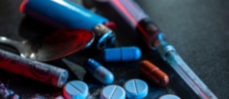 Stock photo of substance use materials including a needle, pills, dollar bill, and spoon