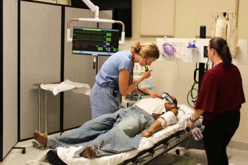A resident listens to the heart of a mannequin during a training session