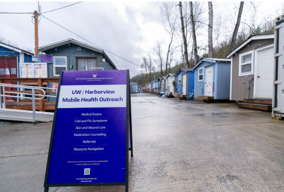 A poster for the Mobile Health Clinic stands in the middle of a tiny home village.
