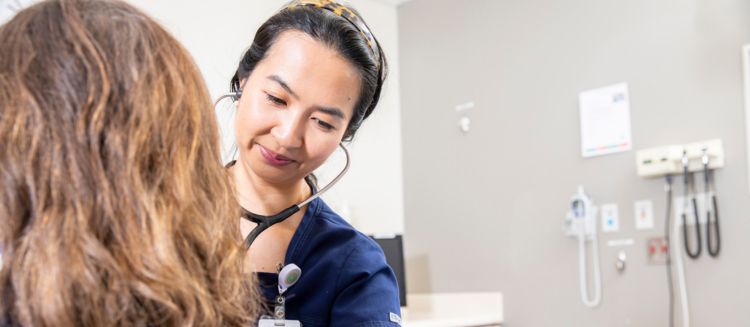 A doctor listens to a patients heart through a stethoscope. 