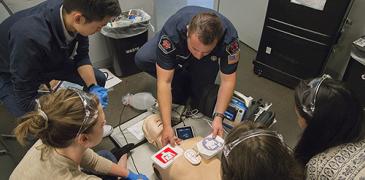 A paramedic practices CPR on a dummy.