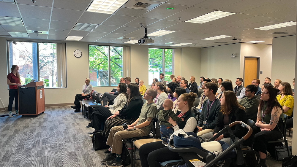 The audience watches a presenter at the research showcase