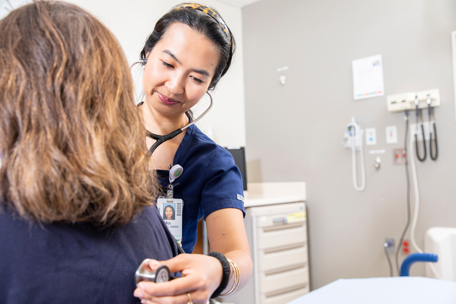 A doctor listens to a patients heart through a stethoscope. 